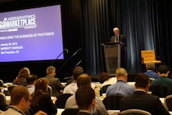 FIGURE 1. Conard Holton, Editor in Chief of Laser Focus World, kicks off the 30th Lasers &amp; Photonics Marketplace Seminar, thanking sponsors and introducing the agenda for the day; the Seminar attracted a record number of attendees to take advantage of a banner time in lasers and photonics.