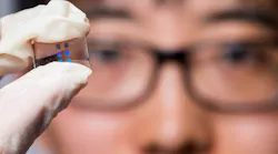 Kai Wang holds a sample containing multiple metasurface camera lenses.