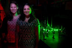 Angela 'Nikki' Chang and Jessica Barrios stand in front of an optical tweezers apparatus that Chang is using to study nanoparticles used in cancer therapy. Angela 'Nikki' Chang and Jessica Barrios stand in front of an optical tweezers apparatus that Chang is using to study nanoparticles used in cancer therapy.