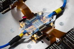 FIGURE 1. Photonic assembly of the 12-mode universal quantum photonic processor. The photonic integrated circuit (PIC) is optically and electrically interfaced—featuring more than 150 tuning elements for full programmability. FIGURE 1. Photonic assembly of the 12-mode universal quantum photonic processor. The photonic integrated circuit (PIC) is optically and electrically interfaced—featuring more than 150 tuning elements for full programmability.