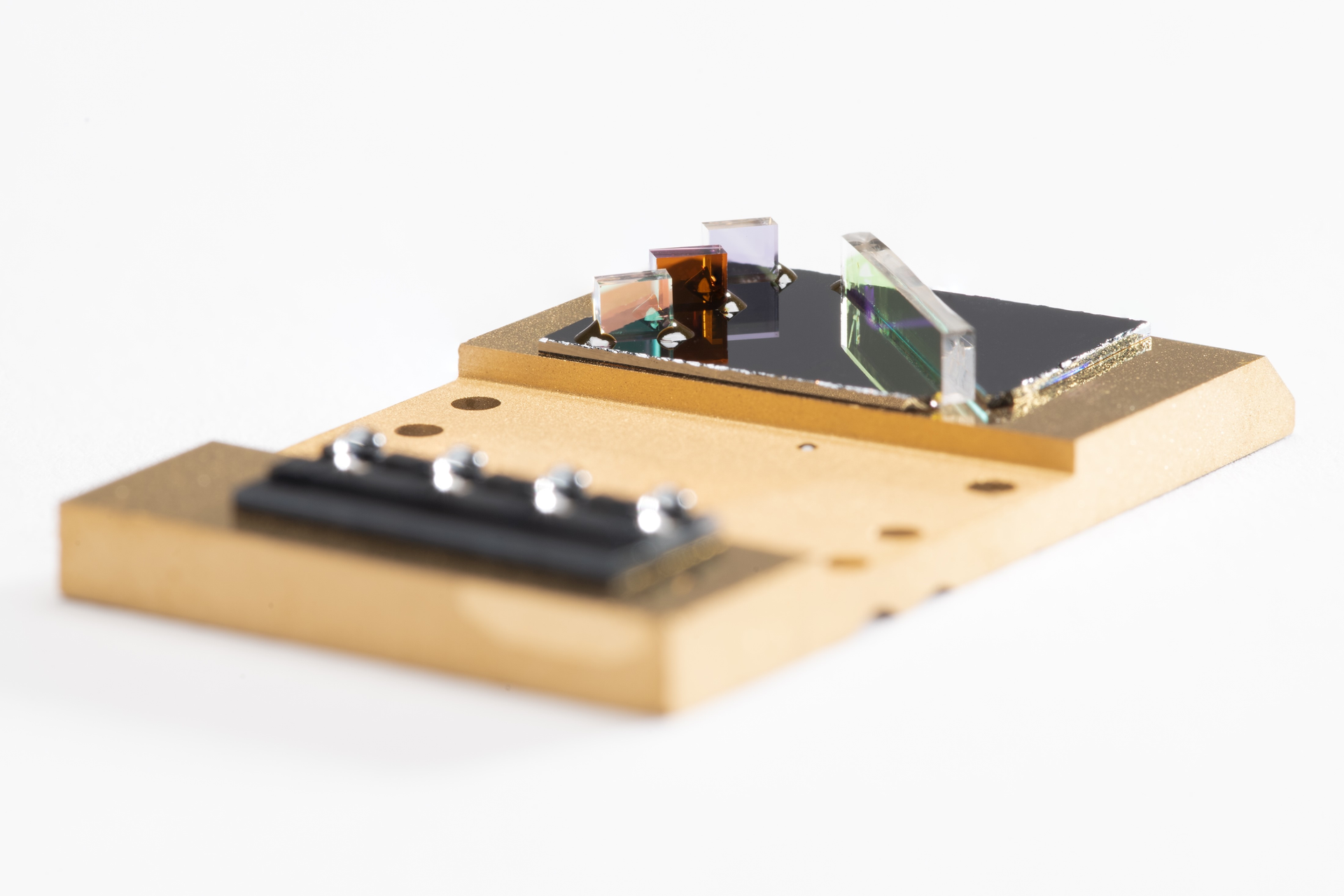 FIGURE 1. Draper&rsquo;s new packaging and assembly approach enables multiple lenses and beamsplitters to be dropped onto an etched silicon topography, along with pieces of low-melting-temperature solid-glass frit, prefabricated into 3D shapes.