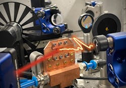 FIGURE 1. When pumped with femtosecond infrared laser pulses (red beam), the quantum well emitter in a water-cooled copper mount generates nearly unipolar terahertz waveforms (orange). FIGURE 1. When pumped with femtosecond infrared laser pulses (red beam), the quantum well emitter in a water-cooled copper mount generates nearly unipolar terahertz waveforms (orange).