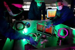 (L-R) Laser engineer Lauren Weinberg, research scientist John Nees, and research engineer Galina Kalinchenko pose for photos while working on the ZEUS laser at the NSF ZEUS laser facility in a Michigan Engineering lab.