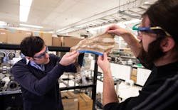 FIGURE 2. Professor Max Shtein (left) and Brian Iezzi, a postdoctoral researcher, analyze the fabric with photonic fibers woven into it at the University of Michigan’s North Campus Research Center in Ann Arbor, MI. FIGURE 2. Professor Max Shtein (left) and Brian Iezzi, a postdoctoral researcher, analyze the fabric with photonic fibers woven into it at the University of Michigan’s North Campus Research Center in Ann Arbor, MI.