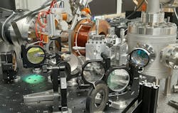 The electron beam travels from left to right and, in the cylindrical vacuum chamber on the right, laser-modulated into few-attosecond-long pulses by two-photon transitions. The electron beam travels from left to right and, in the cylindrical vacuum chamber on the right, laser-modulated into few-attosecond-long pulses by two-photon transitions.