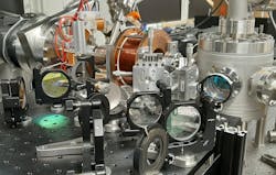 The electron beam travels from left to right and, in the cylindrical vacuum chamber on the right, laser-modulated into few-attosecond-long pulses by two-photon transitions.