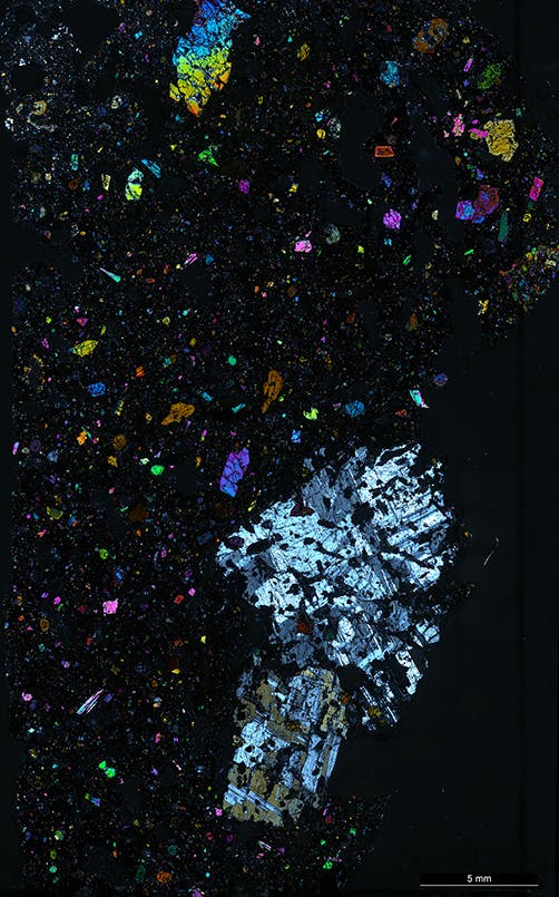 FIGURE 2. Microscope view of lava, which shows large colorful crystals in fine-grained black rock matrix that can be analyzed using the laser approach.