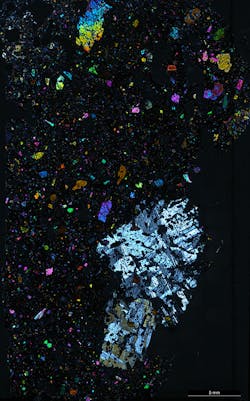 FIGURE 2. Microscope view of lava, which shows large colorful crystals in fine-grained black rock matrix that can be analyzed using the laser approach. FIGURE 2. Microscope view of lava, which shows large colorful crystals in fine-grained black rock matrix that can be analyzed using the laser approach.