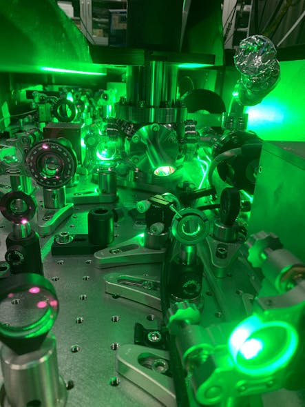 FIGURE 3. A view inside the amplifier. High-energy ultrafast pulses (red) are produced by chirped-pulse amplification. At the image&rsquo;s center is a chamber that contains the cryo-cooled amplifier crystal, which is excited by a (green) pump laser.