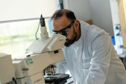A scientist inspecting quantum dot films using an optical microscope.