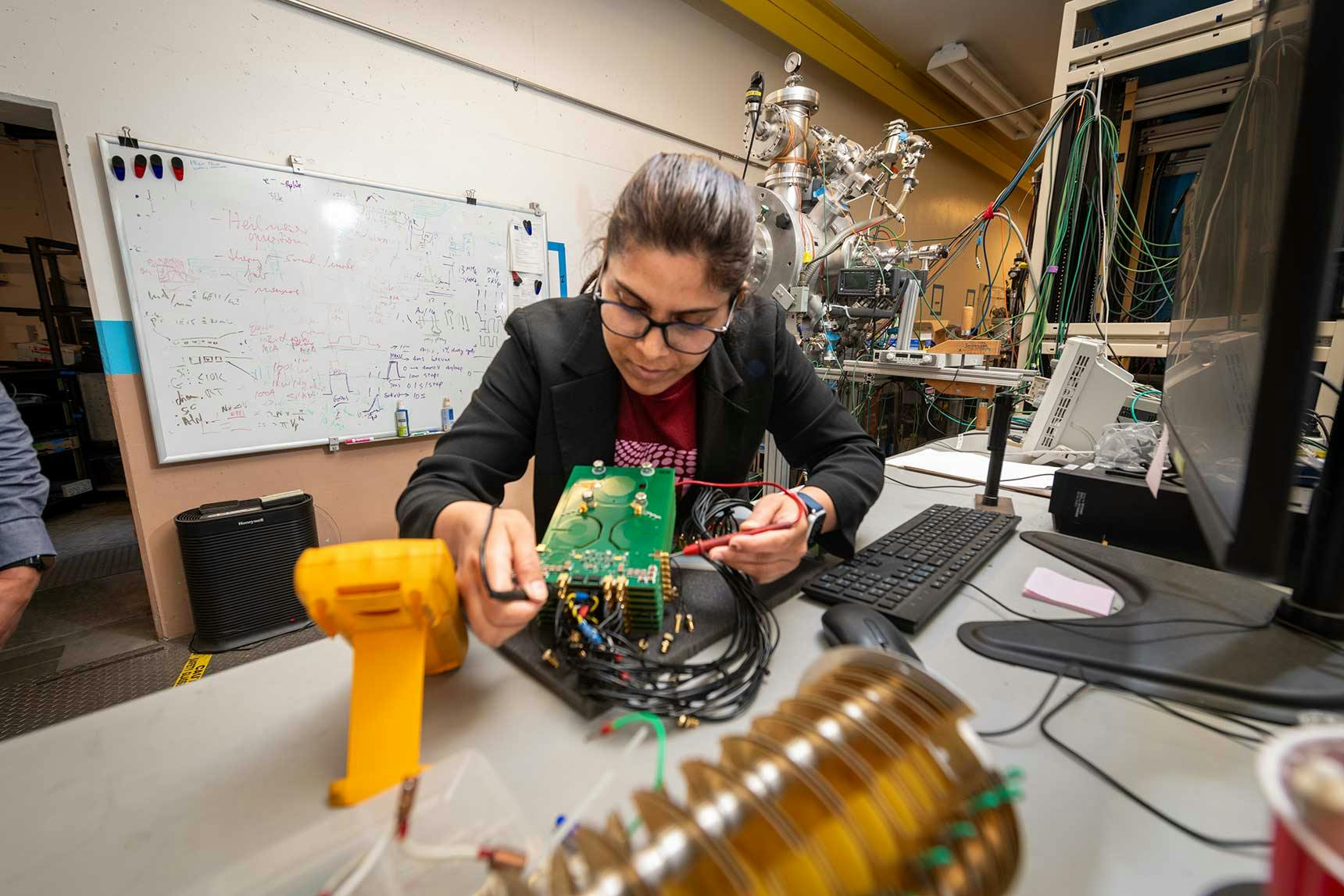 Kaushalya Jhuria, a postdoctoral scholar in Berkeley Lab&rsquo;s Accelerator Technology & Applied Physics Division, testing electronics from the experimental setup used to make qubits in silicon.