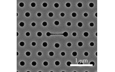This image shows a top view of a photonic-crystal nanolaser biosensor, in which the center narrow slot (horizontal line) is the main part of the sensor. The size variation of the holes is intentional; the hole sizes are all optimized so that the laser's emission is effectively extracted to the top.