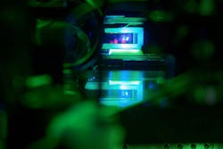 Glass cell with a cloud of laser-cooled strontium atoms hovering above a high-resolution microscope objective in our experiment at the Max Planck Institute of Quantum Optics. Glass cell with a cloud of laser-cooled strontium atoms hovering above a high-resolution microscope objective in our experiment at the Max Planck Institute of Quantum Optics.