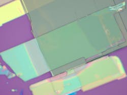 Two thin flakes of niobium oxide dichloride stacked on each other and photographed under a light microscope. One flake’s crystalline grain (gray flake) is positioned perpendicularly to the grain of the other flake (green flake). Two thin flakes of niobium oxide dichloride stacked on each other and photographed under a light microscope. One flake’s crystalline grain (gray flake) is positioned perpendicularly to the grain of the other flake (green flake).