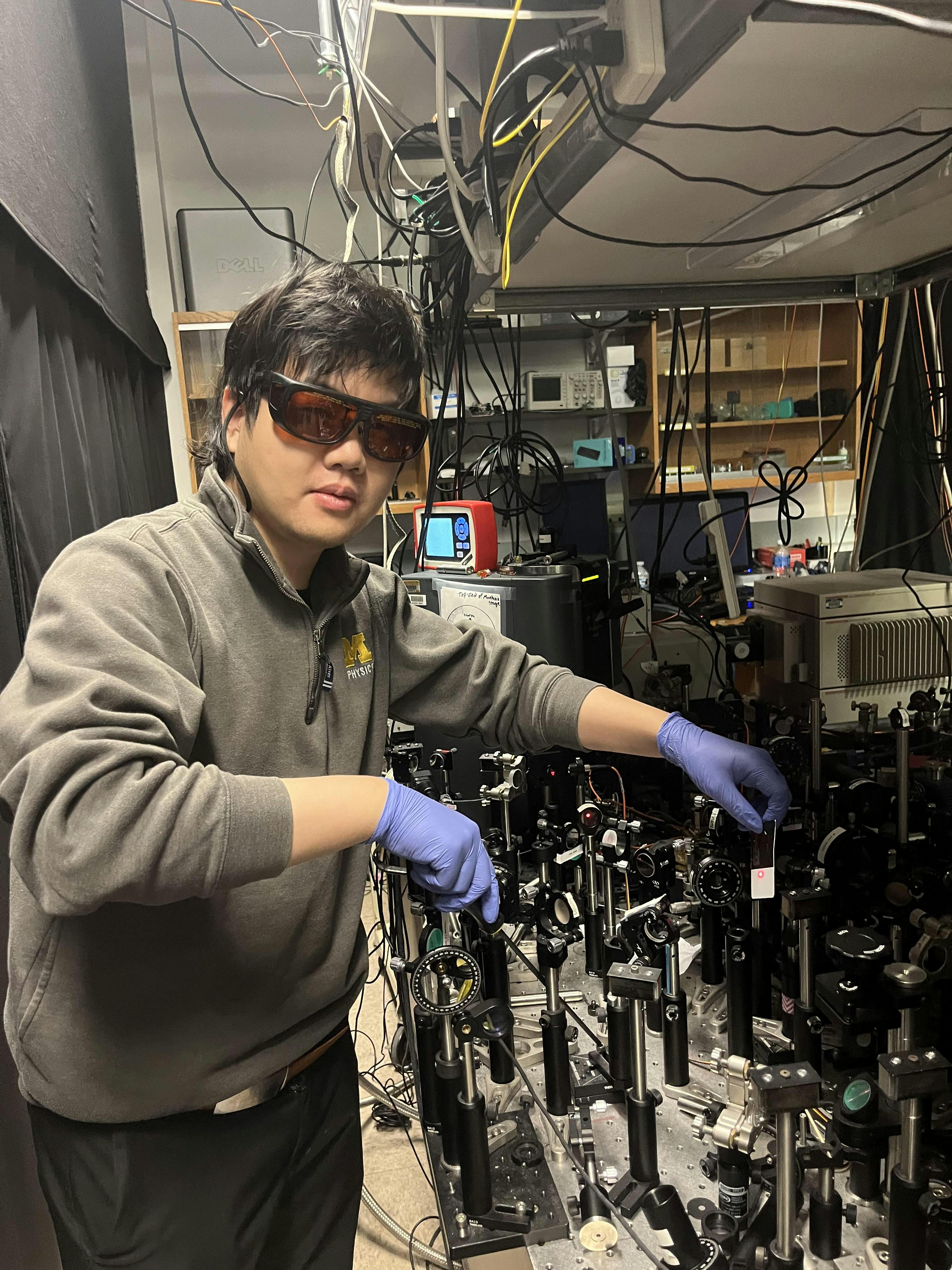 Lingxiao Zhou, a physics Ph.D. student, in the lab with the team&rsquo;s setup.