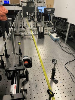 FIGURE 2. Our filamentation-induced disruption experiment was set up on a SCAPA beamline. A HeNe output beam was steered in a counterpropagating direction to the USPL. The HeNe beam had a shallow crossing angle through the USPL-induced filaments. Filaments were generated halfway along the tape measure, to which the USPL traveled parallel. FIGURE 2. Our filamentation-induced disruption experiment was set up on a SCAPA beamline. A HeNe output beam was steered in a counterpropagating direction to the USPL. The HeNe beam had a shallow crossing angle through the USPL-induced filaments. Filaments were generated halfway along the tape measure, to which the USPL traveled parallel.