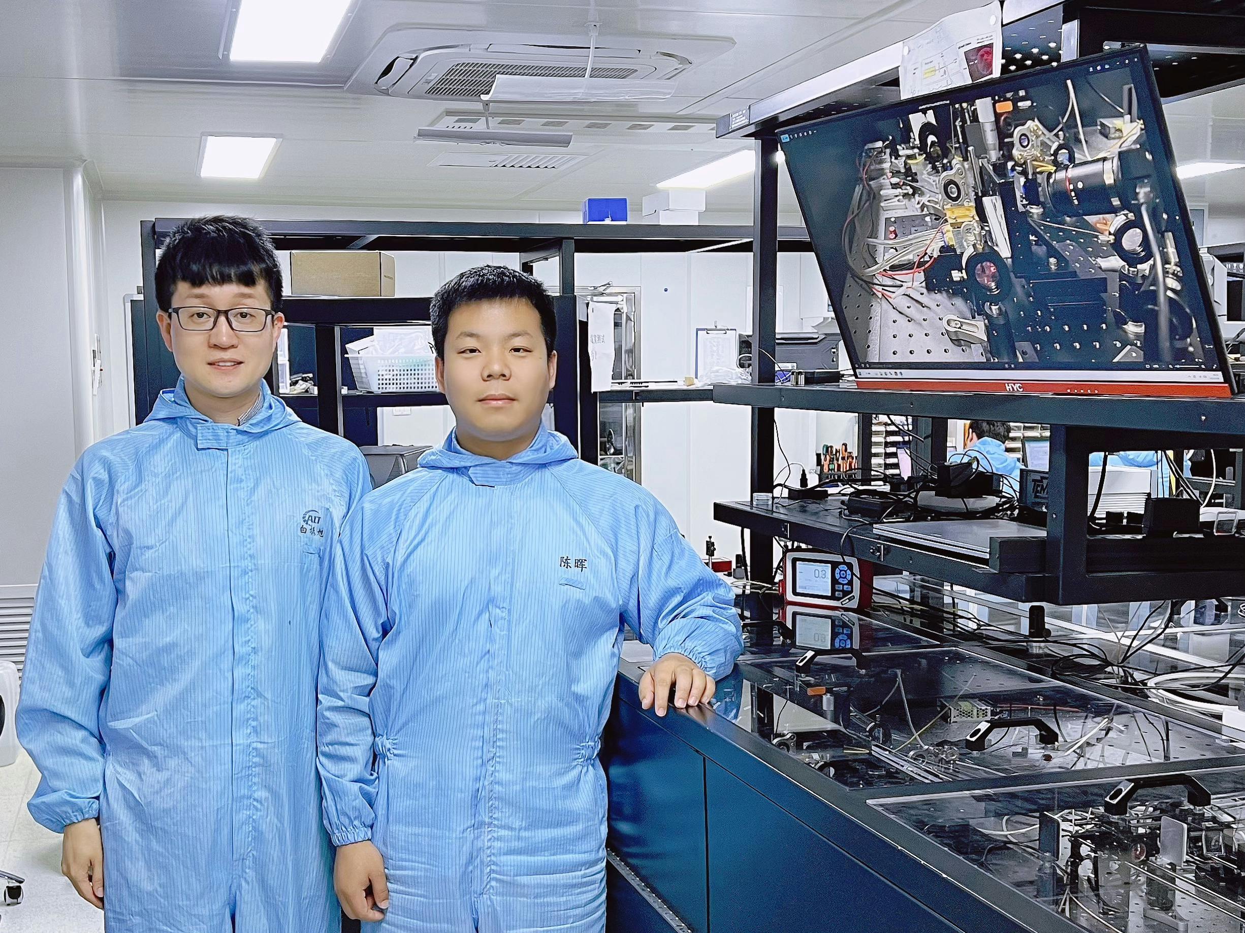 The team&rsquo;s diamond Raman vortex laser experimental optical platform with Zhenxu Bai (left) and Hui Chen (right) of the paper. A physical image of the device is also shown on the right-hand monitor in the background.