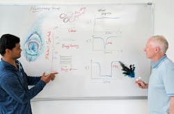 Dr. Seemesh Bhaskar (left) holds a photonic crystal fabricated in the Nanosensors Group and Prof. Brian Cunningham (right) holds a peacock feather, which symbolizes the nanopatterned structures in nature that inspire modern photonics. The whiteboard sketch depicts a cryosoret, glass, and photonic crystals to illustrate the cross-disciplinary fusion of biology, optics, and self-assembly that drives our diagnostics research. Dr. Seemesh Bhaskar (left) holds a photonic crystal fabricated in the Nanosensors Group and Prof. Brian Cunningham (right) holds a peacock feather, which symbolizes the nanopatterned structures in nature that inspire modern photonics. The whiteboard sketch depicts a cryosoret, glass, and photonic crystals to illustrate the cross-disciplinary fusion of biology, optics, and self-assembly that drives our diagnostics research.