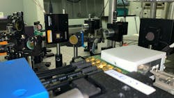 FIGURE 1. Measurement setup at Professor Lobino’s quantum lab at the University of Trento; the chip is inside an oven to control its temperature, while electric signals reach the device through the black SMA cable. Credit: University of Trento FIGURE 1. Measurement setup at Professor Lobino’s quantum lab at the University of Trento; the chip is inside an oven to control its temperature, while electric signals reach the device through the black SMA cable. Credit: University of Trento