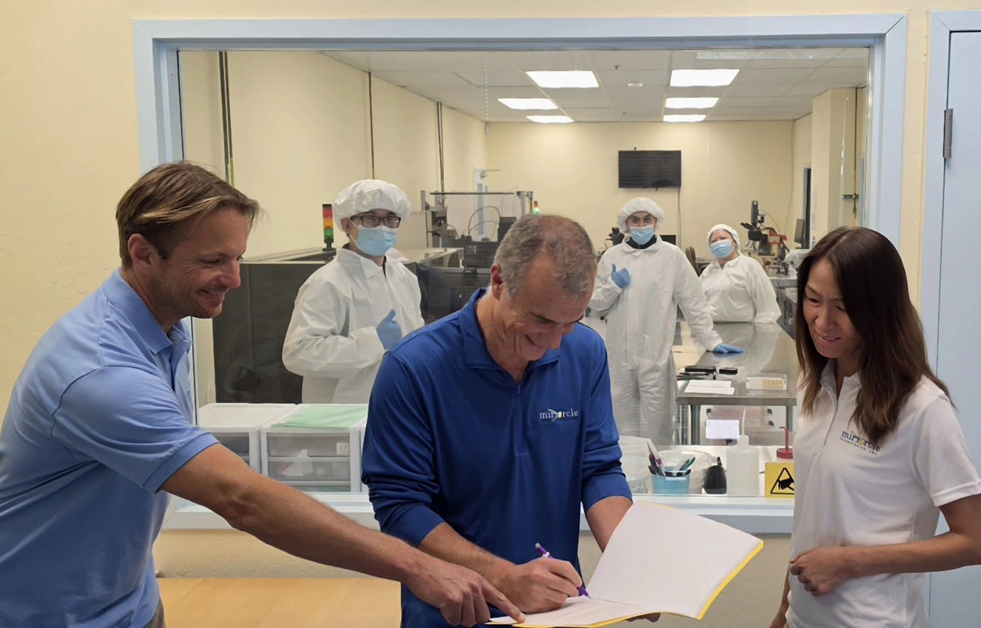 CEO of Mirrorcle Technologies, Dr. Veljko Milanovic singing the document alongside CFO of Mirrorcle Technologies, Peggie Lo, in front of our production clean room viewing area at our Headquarters in Richmond, CA.