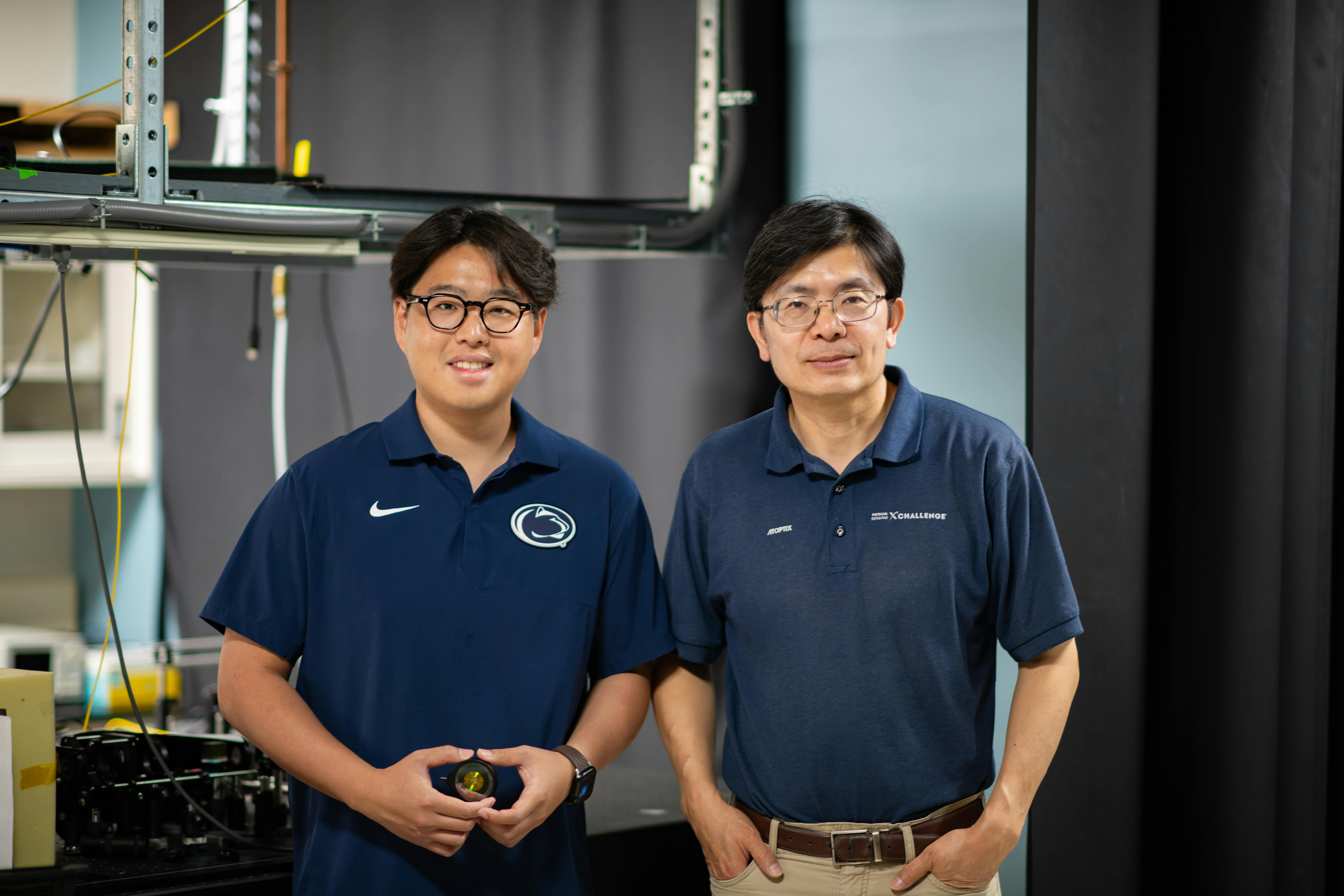 Yu-Jie Lin (left) holds the metalens the group developed, and Professor Zhiwen Liu is on his right.